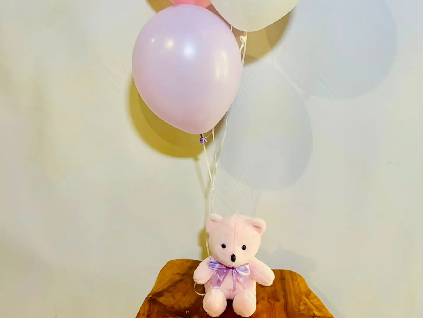 A Small Pink Teddy Bear With Balloons